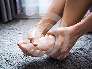 Women suffering from acute foot pain and use hands to massage on feet.