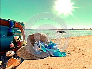 Women summer beachwear   hat and blue  bag flowers and seashells on sand at sea  nature landscape background