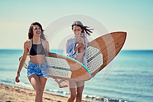 Women surfers walking on the beach and having fun in summer Vacation. Extreme Sport.