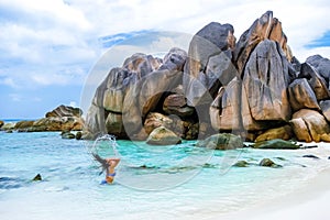 Women swimming at Anse Cocos beach with huge granite boulders at La Digue Seychelles Islands