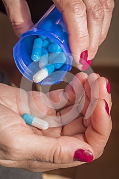 Women take white and blue capsule with left hand