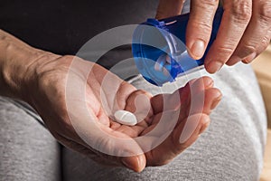 Women take white capsule with left hand from a blue transparent