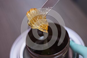 A women takes out from the jar a Pasta for a Sugaring, Yellow color. Depilatory sugar paste. Beauty and cosmetics.