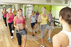 Women Taking Part In Gym Fitness Class Using Weights
