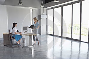 Women Talking At Desk In Empty Office