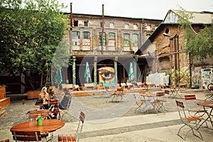 Women talking at outdoor cafe in grunge area with squat and underground clubs