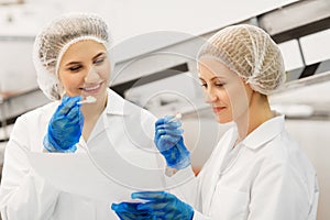 Women technologists tasting ice cream at factory