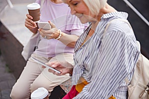 Women texting and drinking coffee in the street