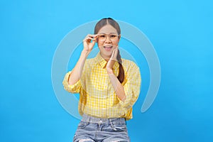 Women touches cheek and glasses with hand while happiness smiling isolated on light blue background