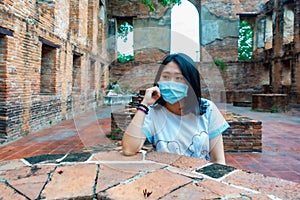 Women tourist at ancient temple in Thailand with  her face mask