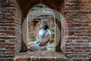 Women tourist at ancient temple in Thailand with  her face mask
