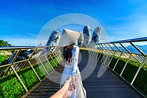 Women tourist holding man\'s hand and leading him to Golden bridge in Da nang, Vietnam