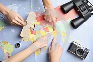 Women with tourist items planning vacation on world map, top view