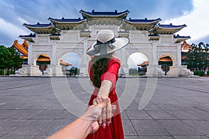 Women tourists holding man`s hand and leading him to Chiang Kai Shek Memorial Hall in Taipei, Taiwan