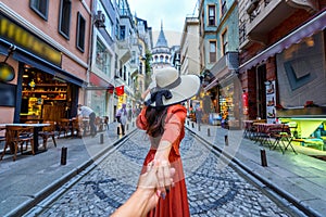 Women tourists holding man`s hand and leading him to Galata tower in Istanbul, Turkey.