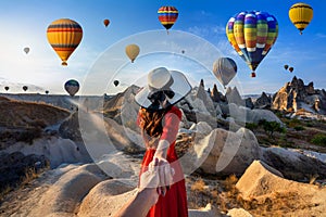 Women tourists holding man`s hand and leading him to hot air balloons in Cappadocia, Turkey. photo