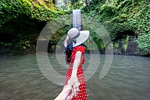 Women tourists holding man`s hand and leading him to Tibumana waterfall in Bali, Indonesia. photo