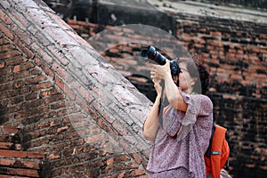Women tourists taking pictures and background ancient brick at Yai Chaimongkol Temple, Thailand