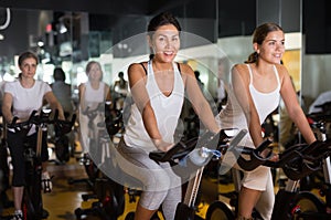 Women training on stationary bikes at gym