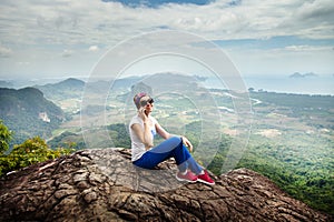 Women travel sit on a cliff on a rich forest mountain. Tab Kak Hang Nak Hill Nature Trail.