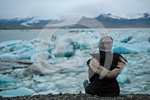 Women traveller sit on the ground and looking at glacier lagoon jokulsarlon