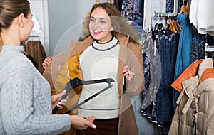 Women trying coat in clothing boutique