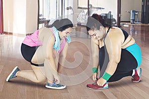 Women tying shoelaces before exercising at gym