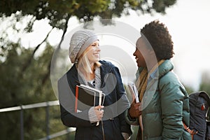 Women, university student and friends with book on campus for sharing, information and notes on research. Classmates