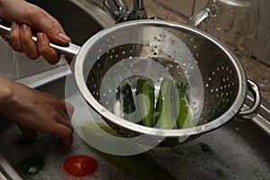 A women using a colander and a kitchen sink to wash marrows.