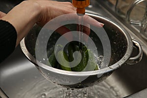 A women using a colander and a kitchen sink to wash marrows.