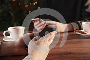 Women using mobile phones at table in cafe, closeup