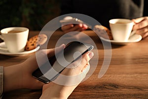 Women using mobile phones at table in cafe, closeup