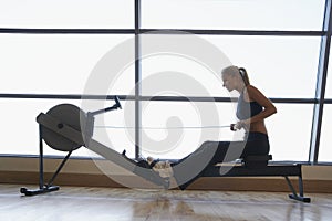 Women Using Rowing Machine In Health Club