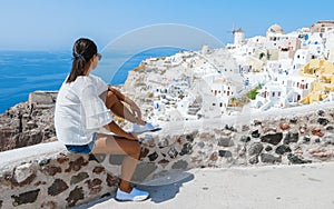 Women visit Oia Santorini Greece on a sunny day during summer with whitewashed homes and churches