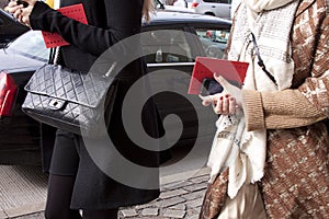 Women walking with designer purse and holding smartphone and invitation