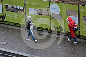 Women walking with hood during Raining day wet street, construction project in fischerinsel