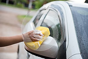 Women washing car with yellow sponge