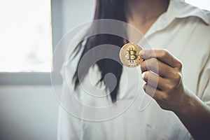 Women wear white shirt holding goden bit coin on left hand, copy