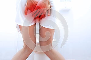 Women wearing white sleepwear, Sitting on the toilet Hand holding the stomach,standing in the toilet, Holding a toilet paper, bent