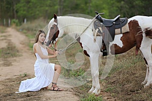 Women on white dress standing by Horses On field Against mountain.