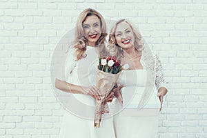 Women in White Dresses with Gift Box and Bouquet.