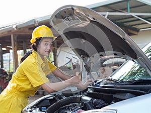 Women in work uniforms are measuring car engine oil levels