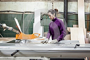 Women worker using saw machine to make furniture at carpenterâ€™s workshop.