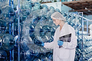 women worker working in drinking water factory inspect counting bottle gallon stock warehouse check counting with hygiene uniform