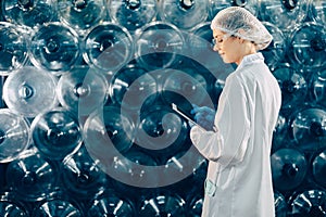 women worker working in drinking water plant factory checking count water bottle gallon in warehouse with hygiene uniform