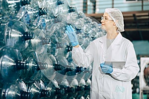 women worker working in drinking water plant factory checking count water bottle gallon in warehouse with hygiene uniform