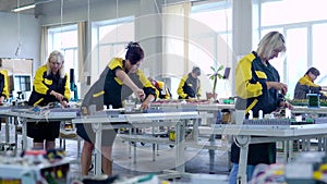 women workers in uniform collect low-voltage and high-voltage equipment in the factory floor. Assembling the filling for