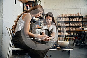 Women working with clay on a potter's wheel in masterful studio