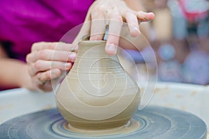 Women working on the potter's wheel. Hands sculpts a cup from clay pot