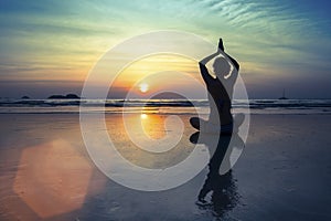Women in Yoga meditation pose at amazing sunset.
